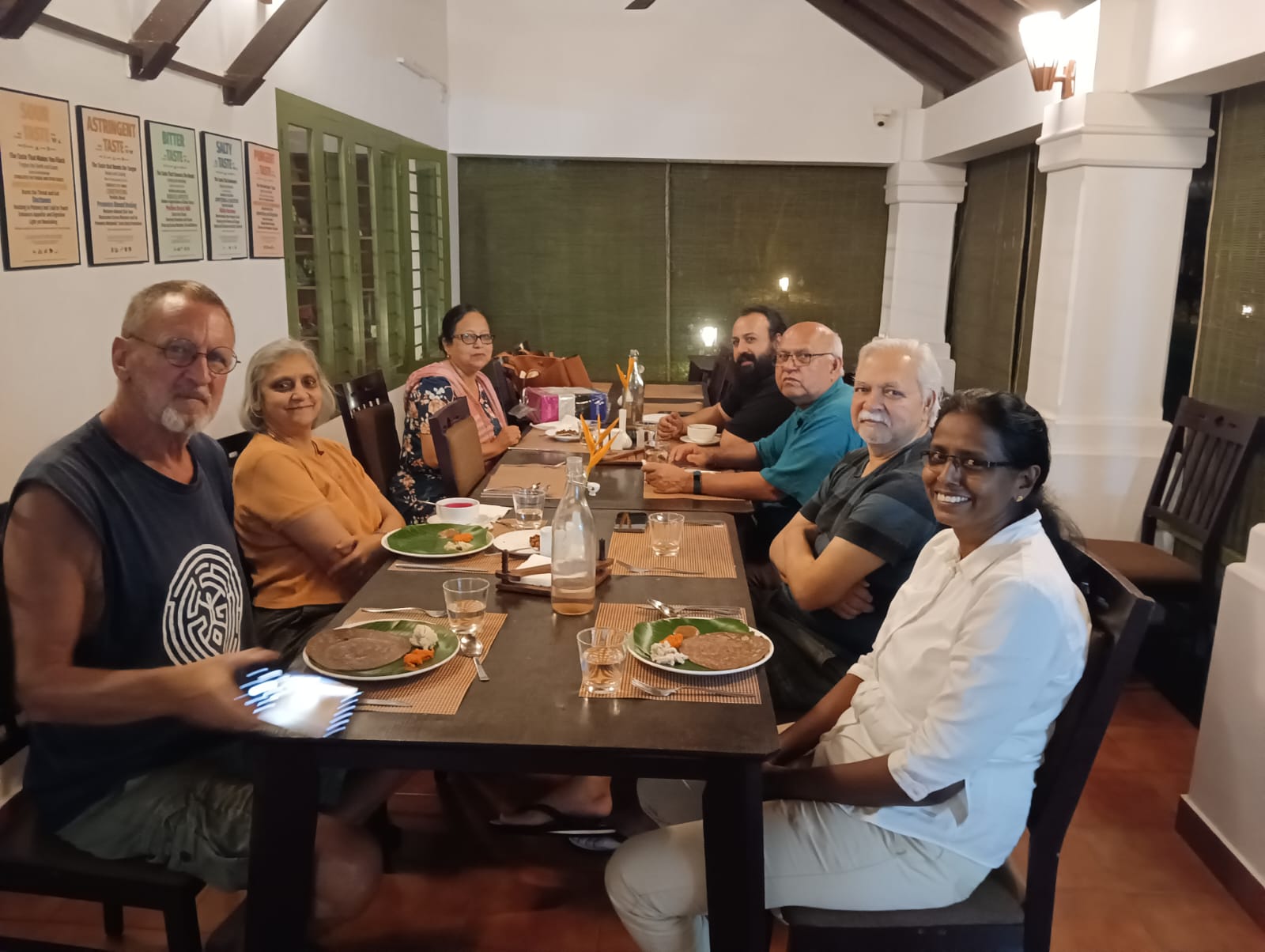 Group of people dining together at a long indoor table.