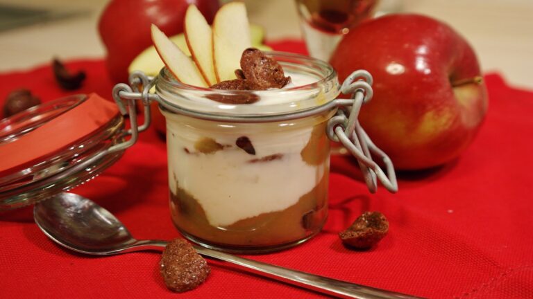 Glass jar dessert with apple slices and raisins on red tablecloth