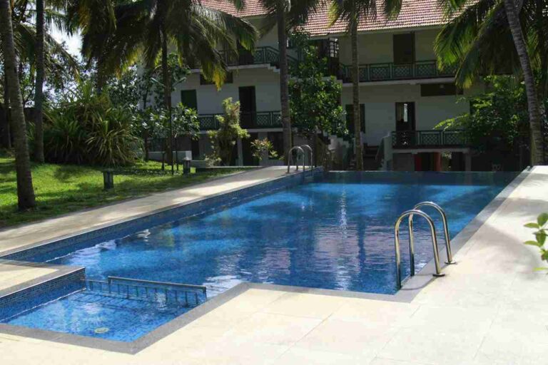 Swimming pool view with coconut trees at Anandakosha wellness resort
