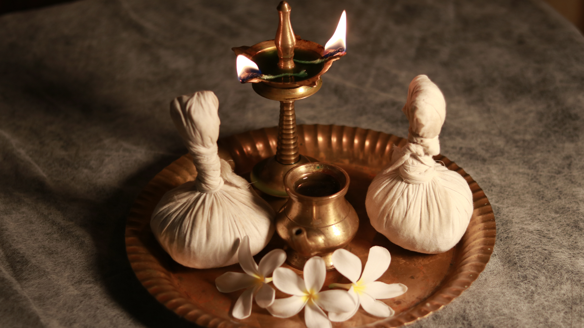Traditional oil lamp with herbal pouches and flowers