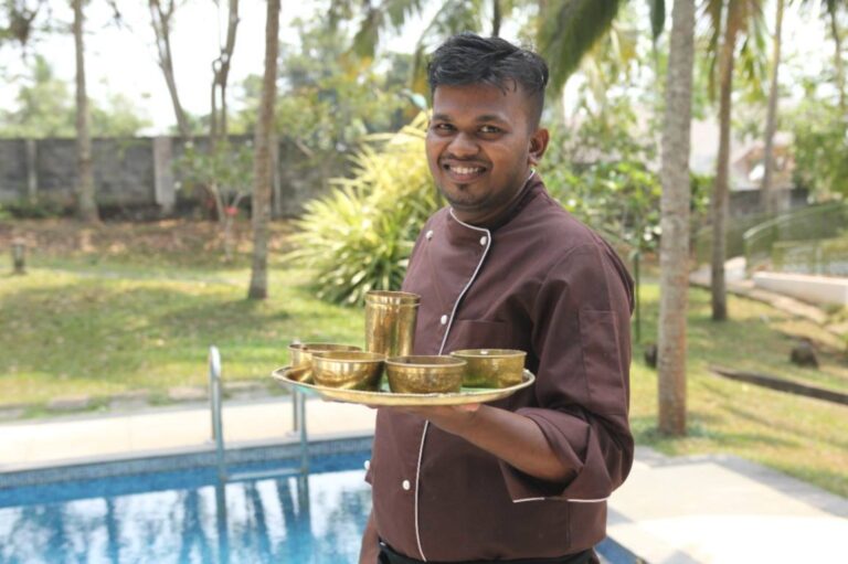 Waiter with an Ayurvedic Indian Thali utensils in hand with a smile