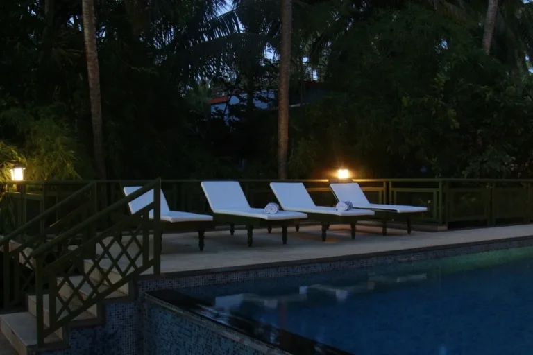 Swimming pool in aanandakosha ayurveda retreat at evening with coconut tree and lamps on